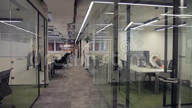 员工用玻璃隔断在现代办公室工作和走动。